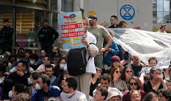 Climate activists gather outside the French asset manager Amundi headquarters to denounce the group's holding in oil major TotalEnergies, Friday, May 24, 2024 in Paris. (AP)