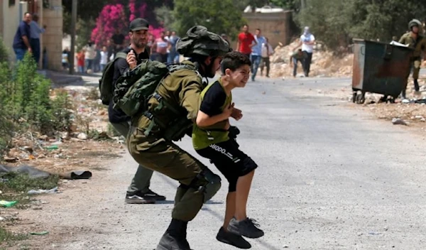 Israeli occupation forces detain a Palestinian child in the Palestinian village of Kfar Qaddum in the occupied West Bank on August 23, 2019. (AFP)