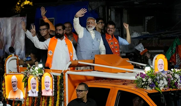 Indian Prime Minister Narendra Modi, center, waves to his supporters from a vehicle during a road show, in Mumbai, India, Wednesday, May 15, 2024. (AP Photo/Rajanish Kakade)