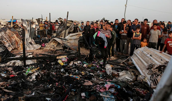 Palestinians look at the destruction after an Israeli strike where displaced people were staying in Rafah, Gaza Strip, occupied Palestine, May 27, 2024 (AP)