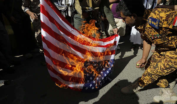 Yemenis burn a US flag during a military march marking the anniversary of Yemeni unity in Sanaa, Yemen, May 22, 2024 (AP)