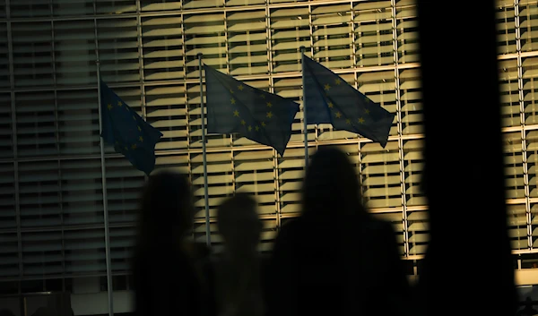 Members of the media look toward EU flags flapping in the wind outside EU headquarters during an EU summit in Brussels, on March 21, 2019. (AP)