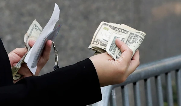 A woman pays with cash as she buys from a street vendor, Sept. 26, 2017 in New York. Despite numbers showing a healthy economy overall, lower-income spenders are showing the strain. (AP)