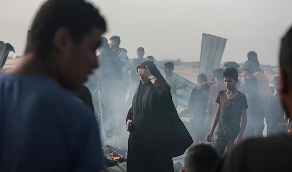 Palestinians look at the destruction after an Israeli strike where displaced people were staying in Rafah, Gaza Strip, Monday, May 27, 2024 (AP)