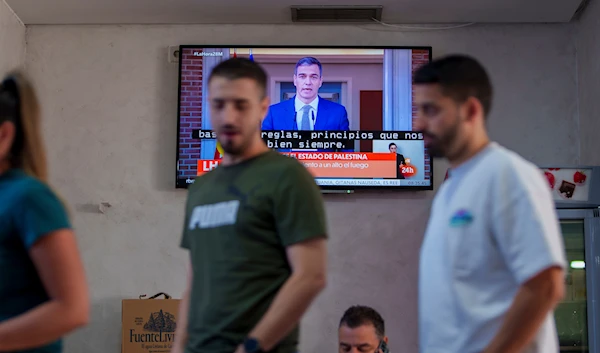 Customers stand in a restaurant while Spanish Prime Minister Pedro Sanchez appears on a television broadcast in Rivas Vaciamadrid, Spain, Tuesday, May 28, 2024. (AP)