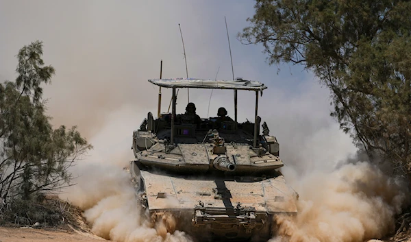 Israeli occupation forces soldiers drive a tank in the Gaza envelope, in southern occupied Palestine, May 29, 2024 (AP)