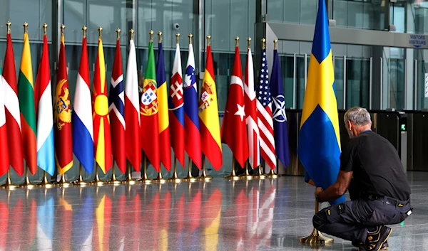 A member of protocol arranges the Swedish flag as protocol prepares for a flag-raising ceremony to mark the accession of Sweden at NATO headquarters in Brussels, Monday, March 11, 2024.(AP)