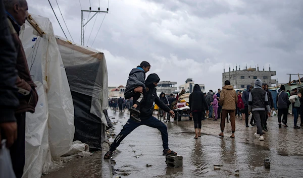 Palestinians displaced by the Israeli air and ground offensive on the Gaza Strip walk through a makeshift tent camp in Rafah on Jan. 27, 2024. (AP)