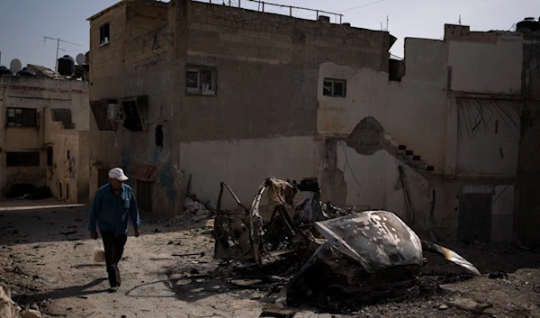 A Palestinian man walks past a detroyed car after an Israeli forces raid in the West Bank Jenin refugee camp, Thursday, May 23, 2024. (AP)