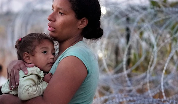 A woman carries her child after she crossed the Rio Grande and entered the US from Mexico to be processed by U.S. Customs and Border Protection, Saturday, Sept. 23, 2023, in Eagle Pass, Texas. (AP)