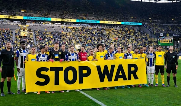 Players holding a banner to protest against Russia's war in Ukraine prior the German Bundesliga soccer match between Borussia Dortmund and Arminia Bielefeld in Dortmund, Germany, Sunday, March 13, 2022. (AP)