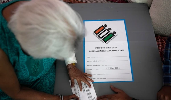 An elderly woman signs a paper after casting her vote at home, in New Delhi, India, on May 17, 2024. (AP)