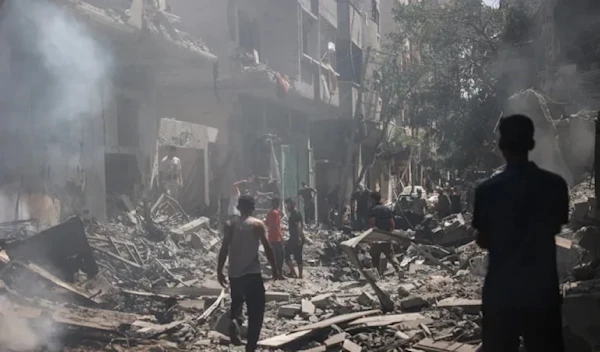 Palestinians walk on the rubble of destroyed buildings following Israeli massacre at the Nuseirat camp, in the central Gaza Strip on June 8, 2024 (AFP)