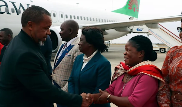 Saulos Chilima, left, greets a gathering at the airport (AP)