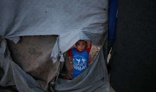 A Palestinian child living in a tent in Rafah after being forcibly displaced with family amid the Israeli genocide (UNRWA)