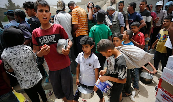 Palestinian children are waiting in line to receive food. (@UNRWA)