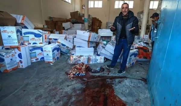 A Palestinian man  gestures near a pool of blood at an UNRWA warehouse and distribution center in Rafah, in the southern Gaza Strip, following an Israeli strike on March 13, 2024. (AFP)