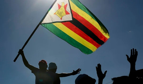 A man is seen raising the national flag of Zimbabwe during a political rally  in Bulawayo, Zimbabwe, Saturday July 21, 2018. (AP)