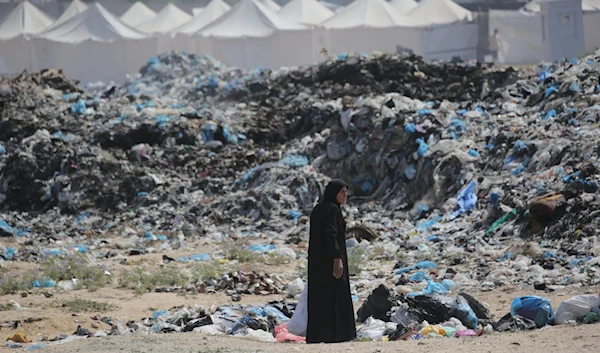 A woman salvaging items from a growing waste dump along a tent displacement camp west of Nuseirat, in central Gaza in May 2024. (AFP)