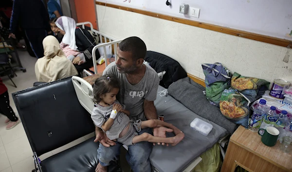 Abdulrahman Al-Rai holds his daughter Hana Al-Rai, 3, who suffers from diabetes, a weakened immune system and malnutrition at Al-Aqsa Martyrs Hospital in Deir al-Balah in the central Gaza Strip, where she is receiving treatment, on June 1, 2024. (AP)