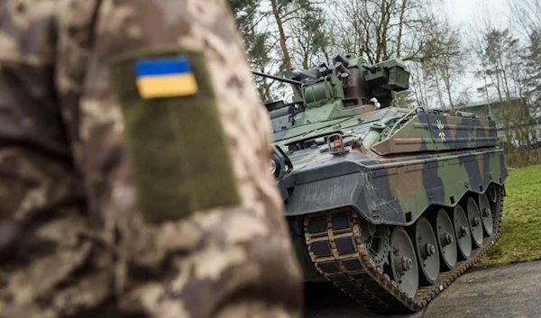 A Ukrainian soldier is standing in front of a Marder infantry fighting vehicle at the German forces Bundeswehr training area in Munster, Germany, on Feb. 20, 2023.