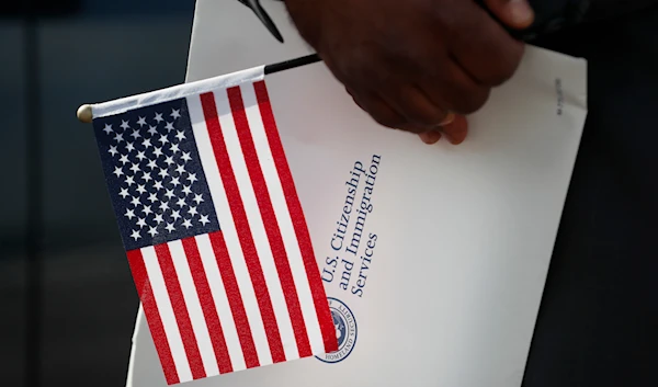 Maweya Babekir, of Iowa City, Iowa, holds a flag before taking the Oath of Allegiance during a drive-thru naturalization ceremony at Principal Park, Friday, June 26, 2020