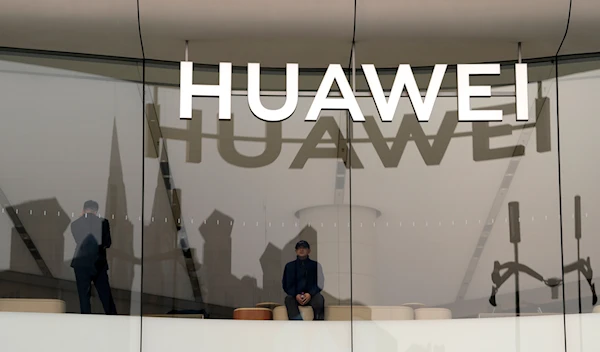 A visitor to store looks out near a logo for Chinese telecoms equipment giant Huawei in Beijing, Tuesday, March 26, 2024. (AP)