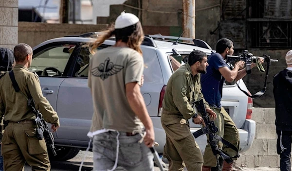 Israeli settlers and soldiers fire at Palestinians side-by side during a raid on the Palestinian town of Huwwara on 12 October 2022. (AFP)