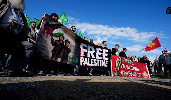 Demonstrators hold banners, condemning the Israeli occupation's genocide in Gaza outside the entrance of RAF Akrotiri, near the southern port city of Limassol, Cyprus, January 14, 2024 (AP)