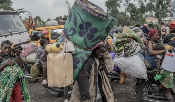 People carry their belongings as they flee eastern DR Congo's Masisi territory (AFP)