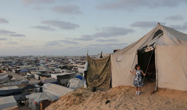 A Palestinian girl stands at the entrance of her family tent at a makeshift tent camp for those displaced by the Israeli air and ground offensive on the Gaza Strip in Khan Younis, Gaza, Tuesday, June 18, 2024. (AP)