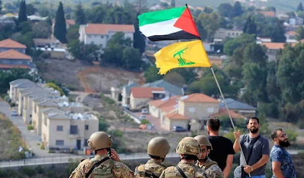 Lebanese soldiers stand at a hill that overlooks the Israeli settlement of Metula, as a man waves the Palestinian and Hezbollah flags, Lebanon, OCT 9, 2023. (AP)