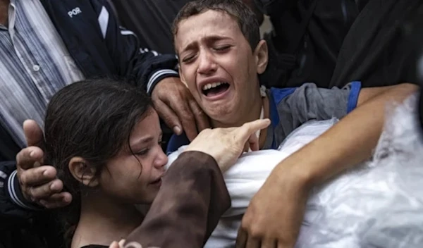 Palestinian children crying while holding the body their mother who was killed in an Israeli airstrike on Gaza in November 2023. (AP)