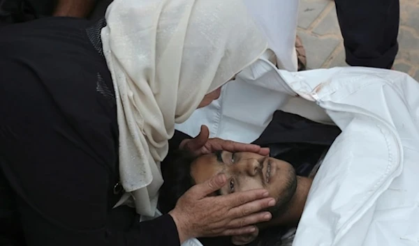 A Palestinian woman takes a last look at a loved one killed by Israeli bombardment, before his burial in Khan Younis, southern Gaza Strip, Friday June 21,2024. (AP)