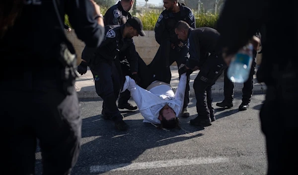 Israeli police officers remove an ultra-Orthodox Jewish man from the street during a protest against army recruitment in Jerusalem on June 2, 2024. (AP)