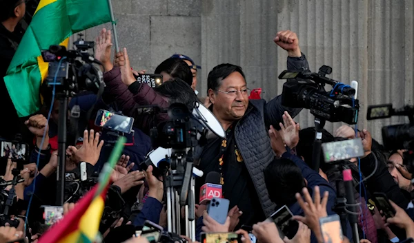 Bolivian President Luis Arce raises a clenched fist surrounded by supporters and media, outside the government palace in La Paz, Bolivia, June 26, 2024 (AP)