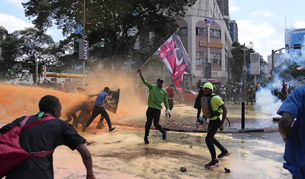 Protesters scatter as Kenya police spray a water canon at them during a protest over proposed tax hikes in a fina