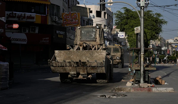 An Israeli bulldozer and an armoured vehicle move on a street during a raid in the occupied West Bank city of Jenin, occupied Palestine, June 6, 2024 (AP)