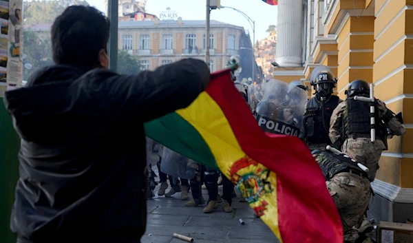 A supporter of President Luis Arce waves a Bolivian flag as soldiers flee from Plaza Murillo, after a failed coup attempt, in La Paz, Bolivia, Wednesday, June 26, 2024. (AP)