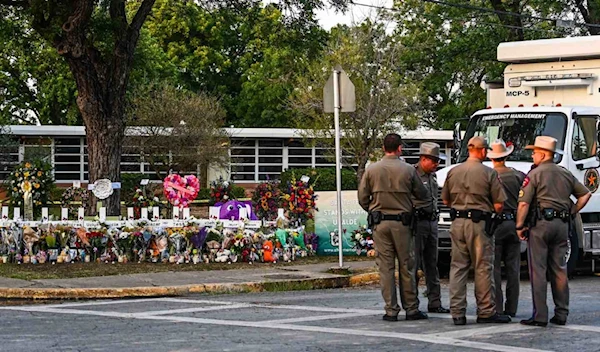 Police officers speak near a makeshift memorial for the shooting victims outside Robb Elementary School in Uvalde, Texas, May 27, 2022. (AFP via Getty Images)