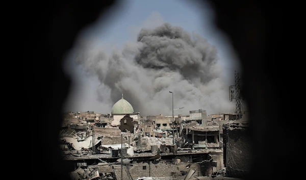 A bomb explodes behind the al-Nuri mosque complex, as seen through a hole in the wall of a house, in Mosul, Iraq, June 29, 2017. (AP)