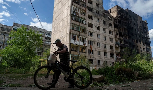 A local man hauls his bicycle in front of an apartment building that was destroyed by a Russian airstrike in Toretsk, Donetsk region, Ukraine, Friday, June 28, 2024. (AP Photo/Evgeniy Maloletka)