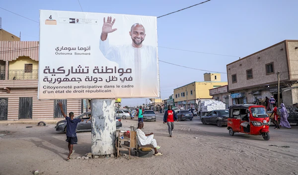 People rest under an electoral banner for presidential candidate Outouma Soumaré ahead of the presidential candidate, in Nouakchott, Mauritania, on June 25, 2024. (AP)