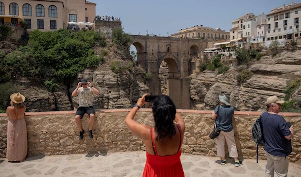 Tourists take photographs of the New Bridge in Ronda, near Malaga, in Spain's southern region of Andalusia, on June 28, 2023. (AP)