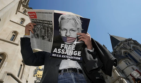 A protester reads a newspaper outside the High Court in London, Monday, May 20, 2024. (AP)