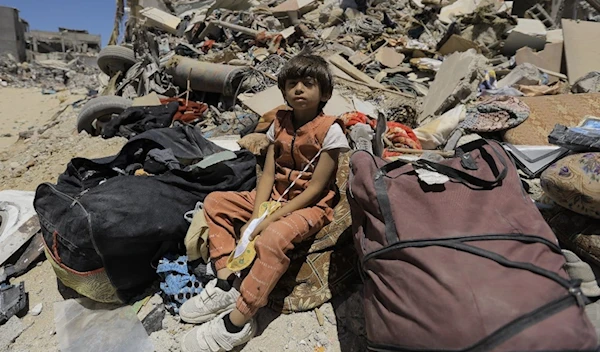 A Palestinian child sitting on the rubble of a residential building bombed by IOF in Gaza (UNRWA)