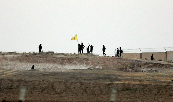 Kurdish fighters with the Kurdish People's Protection Units, or YPG, wave their yellow triangular flag and wave their arms in the outskirts of Tal Abyad, Syria, June 15, 2015 (AP)