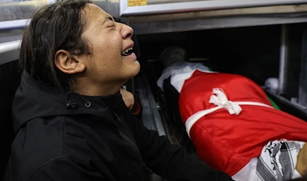 A child mourns over the body of one of five people killed in the occupied West Bank city of Jenin during an overnight Israeli incursion, at the morgue of a hospital on November 26, 2023. (AFP via Getty Images)