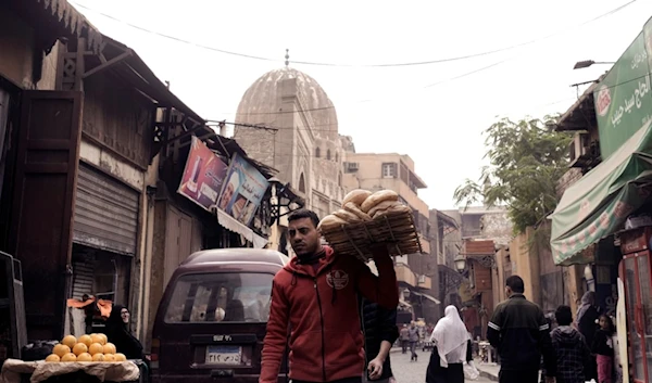 A man balances a tray of traditional "Baladi" flatbread outside a bakery, in the Old Cairo district of Cairo, Egypt, Friday, Dec. 8, 2023. (AP)