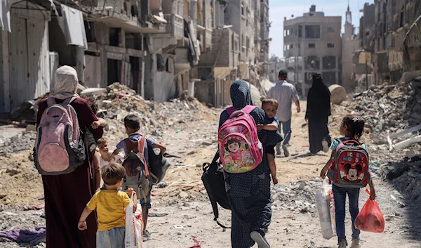 Palestinian women and their children walk though destruction in the wake of an Israeli air and ground offensive in Jabalia, northern Gaza Strip after the Israeli occupation forces withdrew from the area, May 31, 2024 (AP)